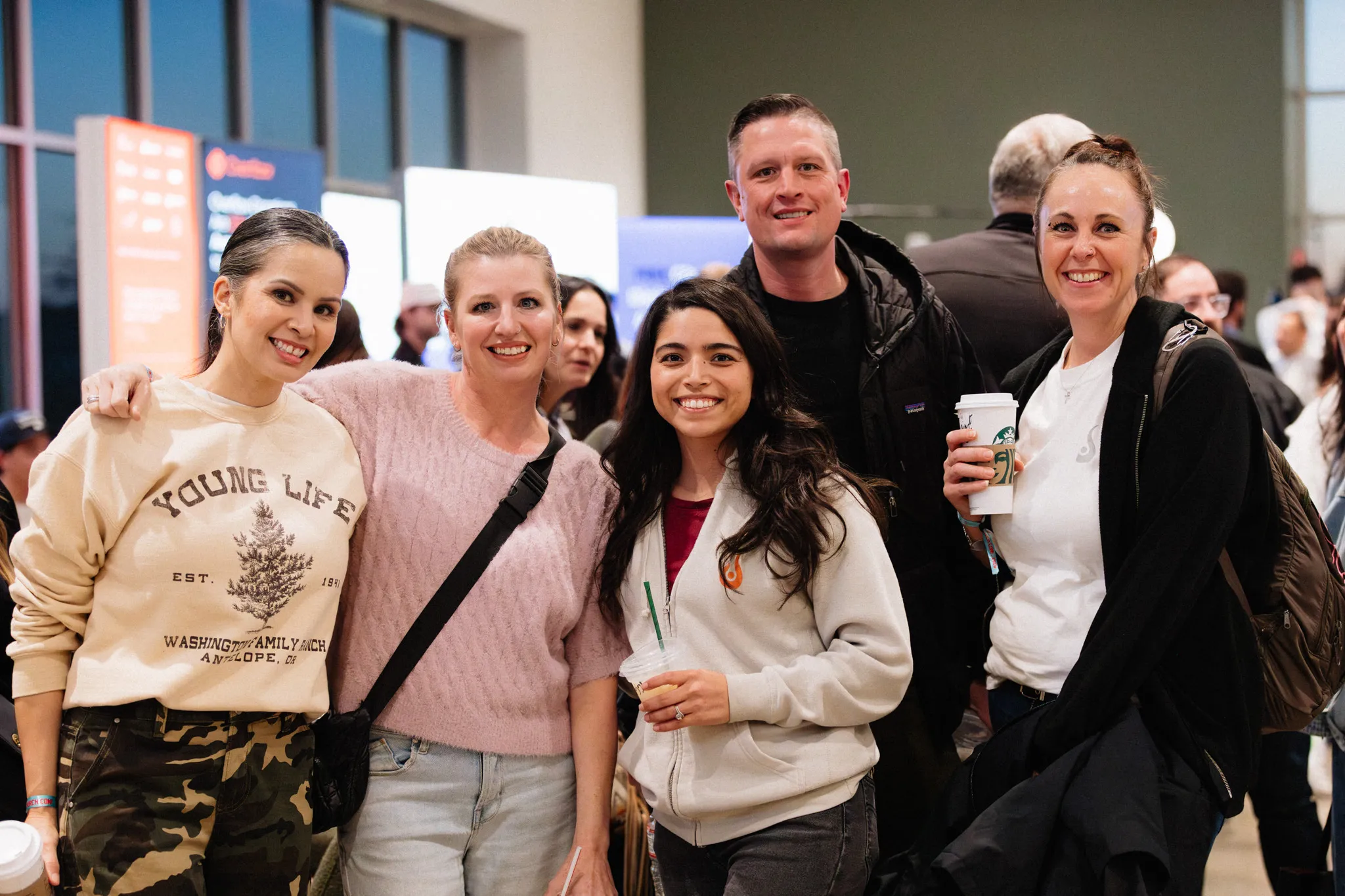 Five friends smile together for a photo in a lobby.